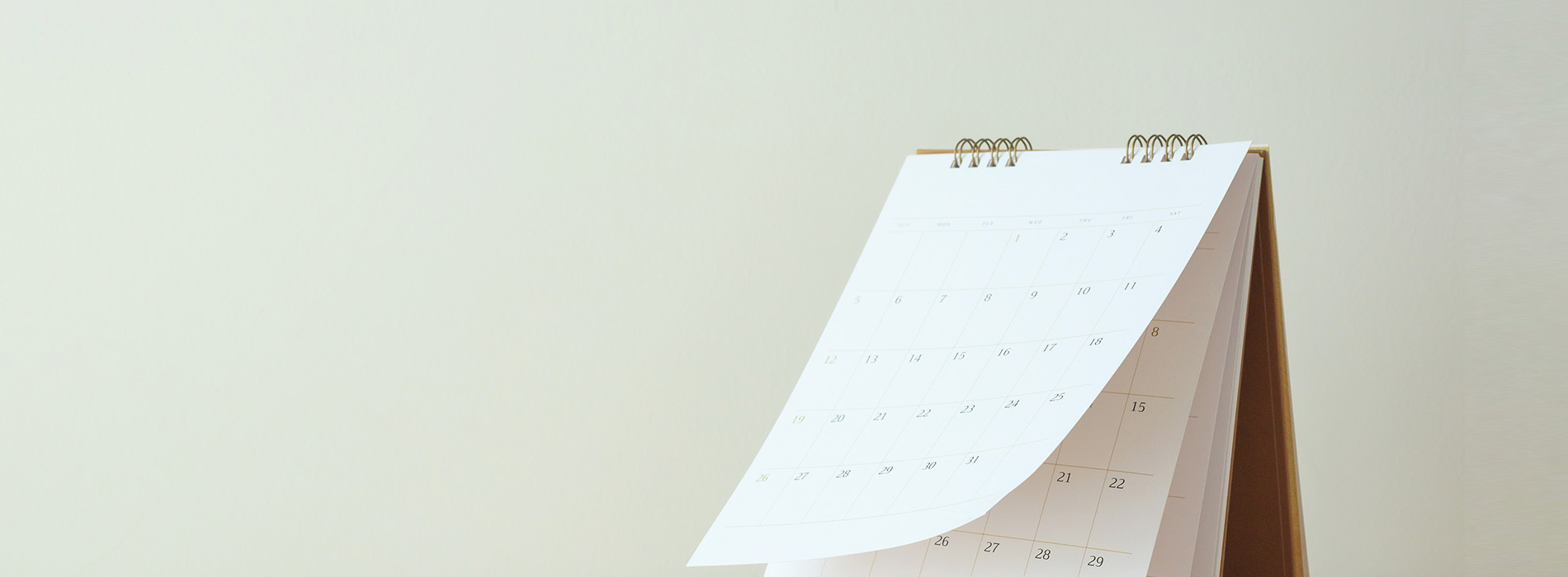 The image shows a calendar with dates visible, sitting on top of what appears to be a spiral-bound notebook or planner.