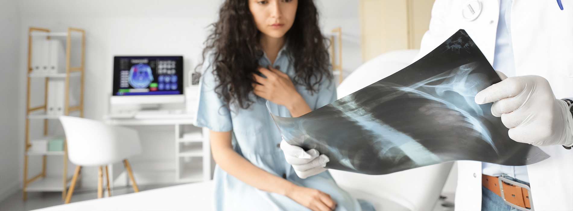 A person standing next to an open medical imaging device displaying a cross-sectional view of the human body, with a healthcare professional present, suggesting a setting for medical consultation or diagnosis.
